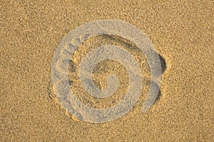 A two foot prints on yellow sand close up