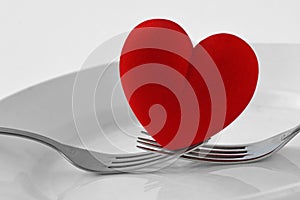 Two forks holding a heart on a plate - Concept of love