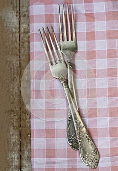 Two forks lie on a pink napkin. The composition stands on a wooden old background
