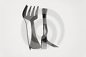 Two forks with sharp shadows of sun on a white background. Menu design concept.