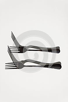Two forks with sharp shadows of sun on a white background. Menu design concept.