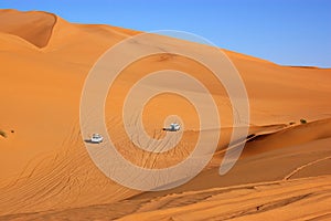 Two four wheel drive vehicles travelling across the Sahara Desert, Libya