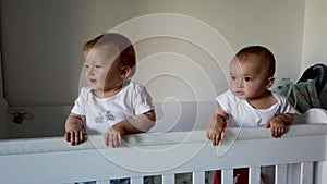 Two fraternal twins sisters laughing, having fun in crib.