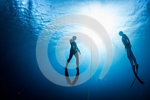 Two free divers ascending from the depth