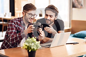 Two freelancer men looking at photos at laptop at desk.