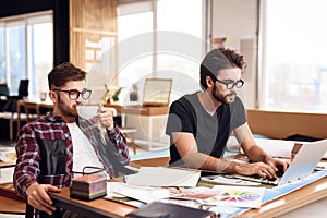 Two freelancer men working at laptop and drinking coffee at desk. photo