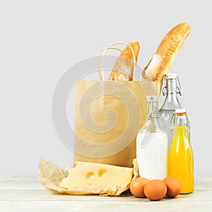 Two french baguette bread loafs in paper bag and dairy produce