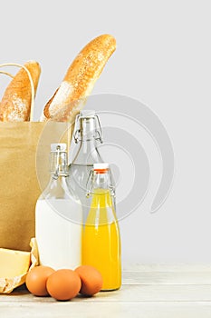 Two french baguette bread loafs in paper bag and dairy produce