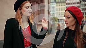 Two french women compete evaluating each other, but begin to smile at each other