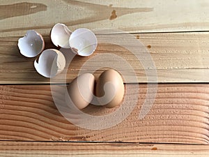 Two fresh chicken eggs with four pieces of eggshells