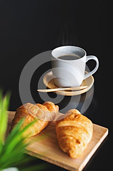 Two fresh croissants and cup of coffee on dark stone table