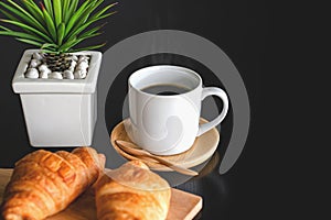 Two fresh croissants and cup of coffee on dark stone table