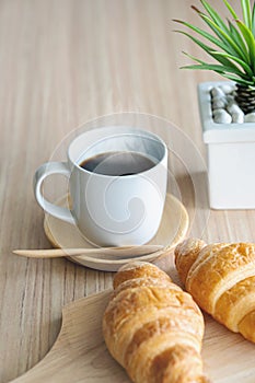 Two fresh croissants and cup of coffee on dark stone table