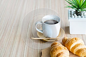 Two fresh croissants and cup of coffee on dark stone table