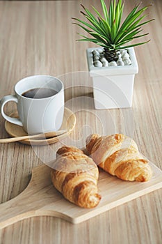 Two fresh croissants and cup of coffee on dark stone table