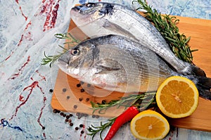 Two Fresh Dorado fish with lemon, onion and rosemary on white background