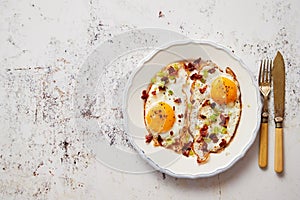 Two fresh fried eggs with crunchy crisp bacon and chive served on rustic plate