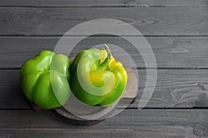 Two fresh green bell peppers on dark wooden table background