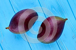 Two fresh mangoes on blue wooden background.