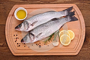 Two fresh moronidae fish on cutting board with ingredients