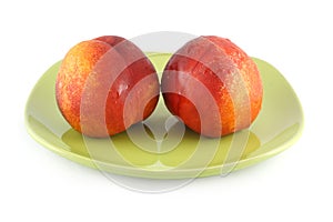 Two fresh peach on a green plate