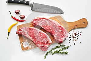 Two fresh raw striploin steak on wooden board