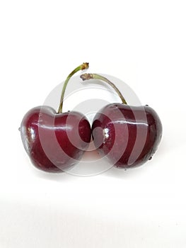 Two fresh red cherries on the white background