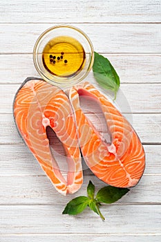 Two fresh salmon steaks with olive oil and Basil on a wooden white background - diet and healthy food