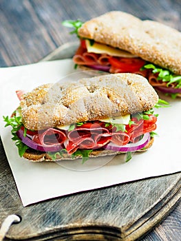 Two fresh sandwiches with jamon, cheese, tomato, lettuce and onion in whole-grain biscuits