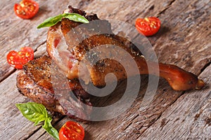 Two fried duck legs and basil, cherry tomatoes closeup on table