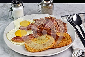 two fried eggs with bacon and hash browns