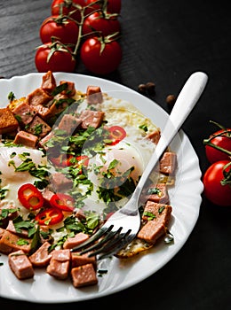 Two fried eggs with ham on dark wooden background