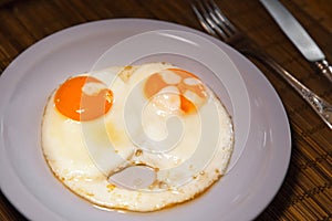 Two fried eggs on plate. Wooden table.