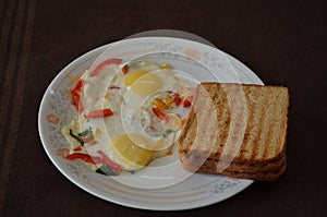 Two fried eggs sunny side up cooked on saute vegetables Three grilled toast of high fibre brown bread. Food breakfast