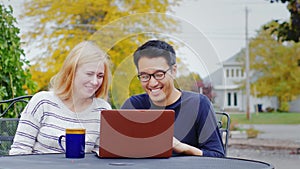 Two friend multiethnicity - Korean man and a Caucasian woman working together or watching a video on a laptop.