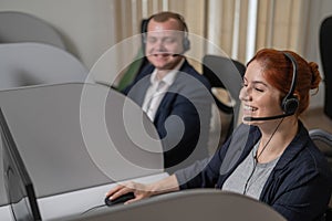 Two friendly call center employees answer customers by phone. Man and woman woman talking on a headset in the office.