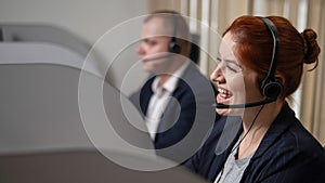 Two friendly call center employees answer customers by phone. Man and woman woman talking on a headset in the office.