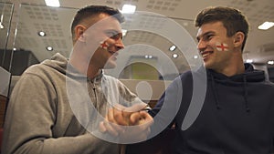 Two friendly football fans unexpectedly meet before match, male leisure activity