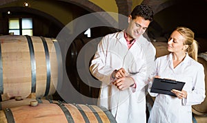 Two friendly wine house workers checking quality of product