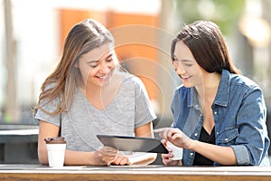 Two friends checking tablet content in a park