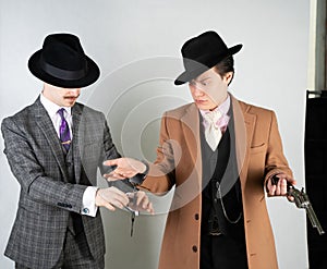 Two friends dressed in vintage clothes and depict retro detectives and spies in English classic style on a white studio background