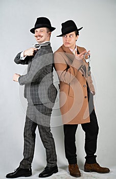 Two friends dressed in vintage clothes and depict retro detectives and spies in English classic style on a white studio background