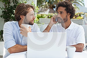 Two friends enjoying coffee together with laptop