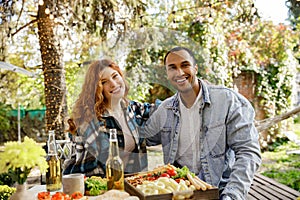 Two friends are having fun on a picnic, telling jokes, drinking drinks. A redhaired girl and an African American oy are