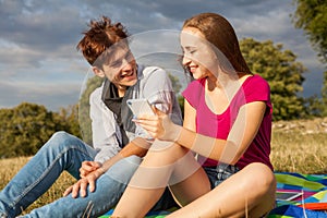 Two friends in a park with mobile phone. Summer time.