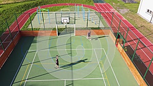 Two friends play one-on-one basketball on an artificial court in summer weather. Active leisure time