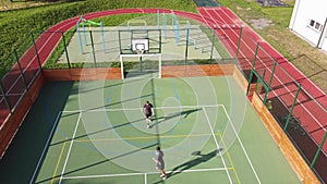 Two friends play one-on-one basketball on an artificial court in summer weather. Active leisure time