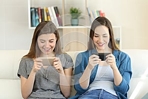 Two friends playing online games with smartphones