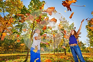 Two friends playing with thrown leaves in forest