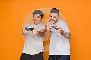 Two Friends Playing Video Games Over Orange Background